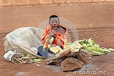 African boy sells corn grill.