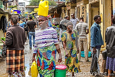 African woman walking with a yellow tank on the head