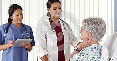 AfricanAmerican doctor talking to elderly woman patient with nurse