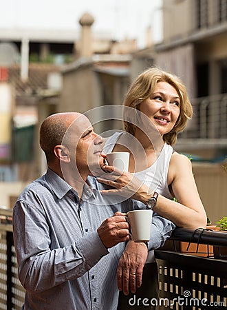 Aged couple drink tea on balcony