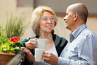 Aged couple drink tea on balcony