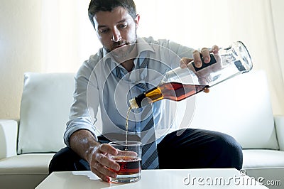 Alcoholic Businessman wearing blue shirt drunk filling up whiskey glass