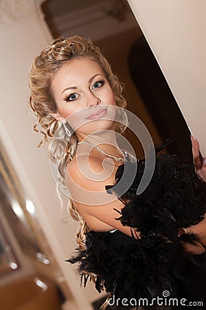 Blonde sexy woman In evening dress in luxury interior. Stylish rich slim girl with hairstyle and bright makeup in apartment.