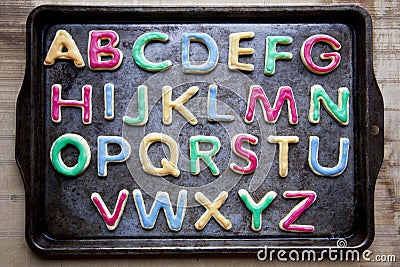Alphabet in decorated colourful cookies on baking tray, horizontal