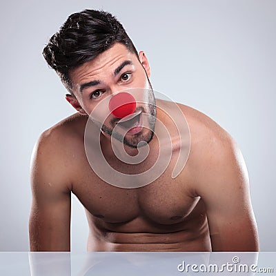 Amazed young naked man with red clown nose