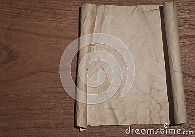 Ancient crumpled paper scroll on wood table for background