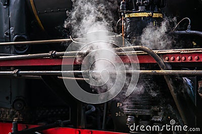 Ancient steam locomotive in steam. Live steam around mechanical