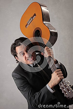 Angry businessman trying to break the guitar