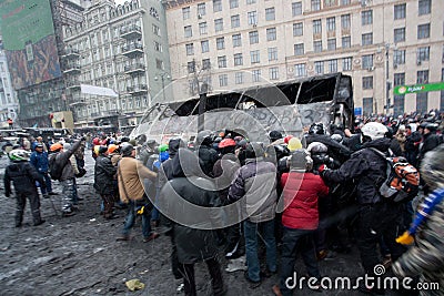 Angry crowd on the occupying street overturned burned-out bus on the demostration during anti-government protest Euromaidan