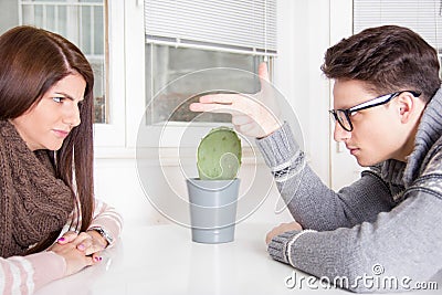 Angry man pointing at woman sitting across the table