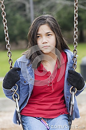 Angry, sad preteen girl on swing