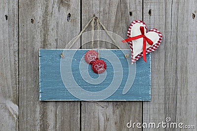 Antique blue sign hanging on wood door with gingham heart and soda pop tops