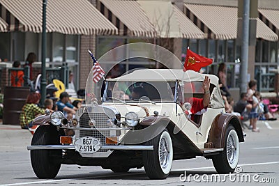Antique car with roof with American Flags in parade in small town America