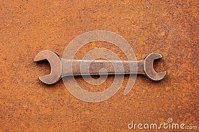 Antique wrench on a rusty background