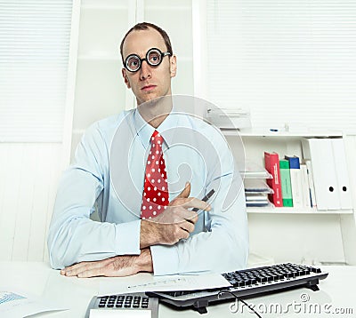 Arrogant man sitting at desk with glasses, a red tie and a blue