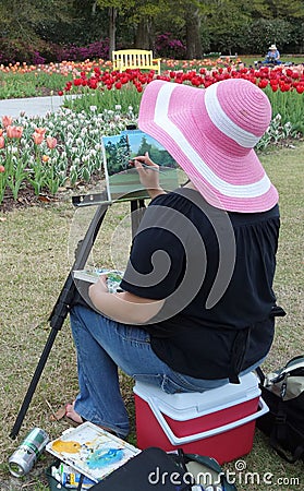 Artist lady sitting and painting outdoors.