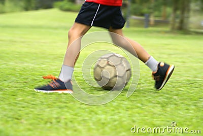 Asian boy kicking soccer ball