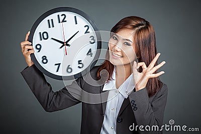 Asian businesswoman hold a clock show OK sign and smile