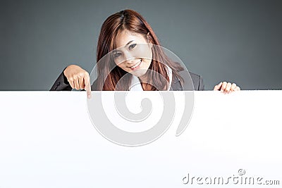 Asian businesswoman stand behind a blank billboard , point down