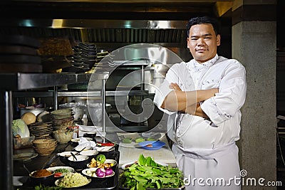 Asian chef smiling at camera in restaurant kitchen