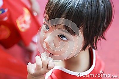 Asian child sucking thumb in dress red cloth