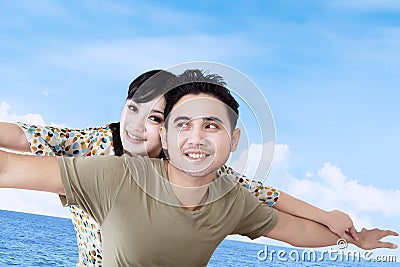 Asian couple pretend to fly over blue sky