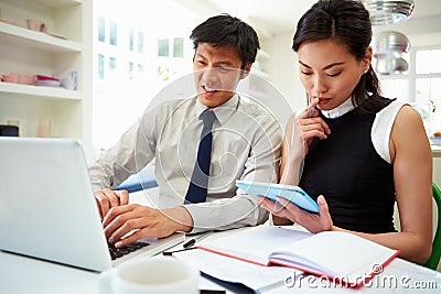 Asian Couple Working From Home Looking At Personal Finances