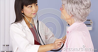 Asian doctor listening to elderly patient s heart