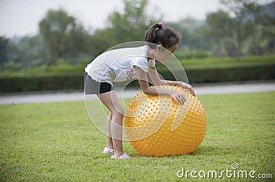 Asian girl play ball in the grass