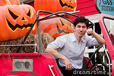 An asian man cross his arm and lean against truck