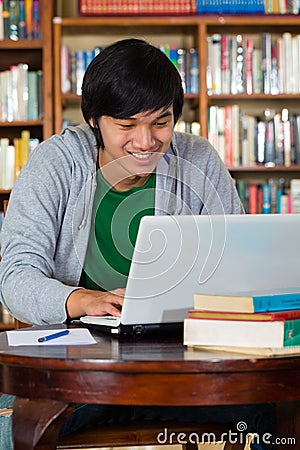 Asian man in library with laptop