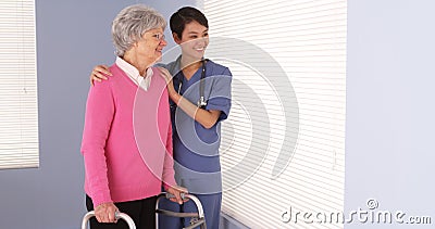 Asian nurse and elderly patient standing by window