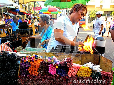 Asian street vendor selling colored candles outside of quiapo church in quiapo, manila, philippines in asia