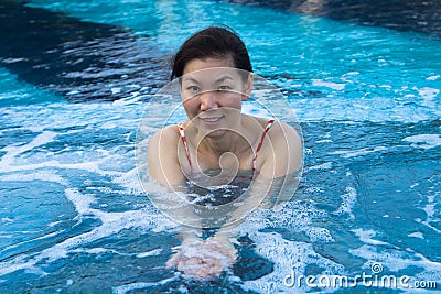 Asian woman enjoying and relaxing in the pool.