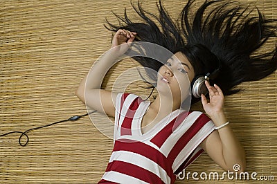 Asian woman laying down listening to music