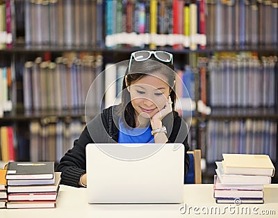 Asian woman in library with laptop