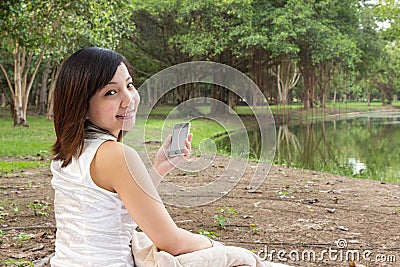 Asian woman with mobile phone and sitting at park