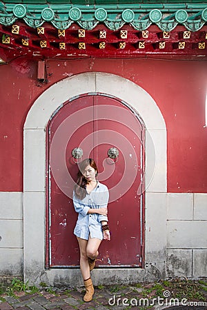 Asian woman standing by red Chinese door
