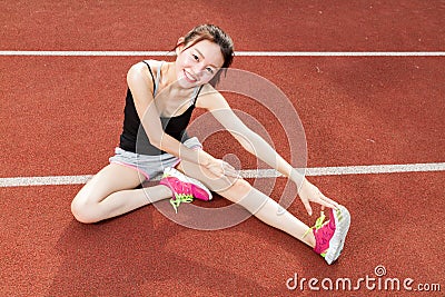 Asian woman stretching on track