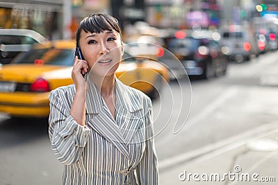 Asian woman talking on cellphone in city