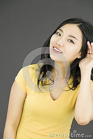 Asian young woman with hand to ear listening