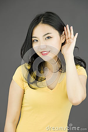 Asian young woman with hand to ear listening