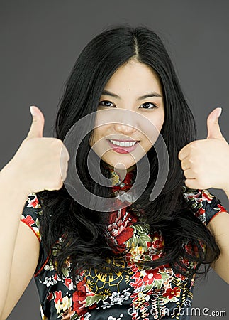 Asian young woman showing thumbs up from both hands on colored background