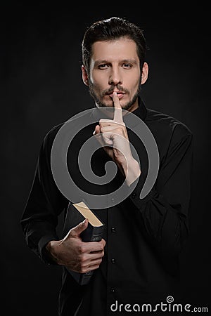 Asking to keep silence. Portrait of priest holding his hand agai