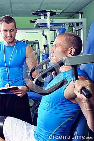 Athlete man in gym with personal fitness trainer