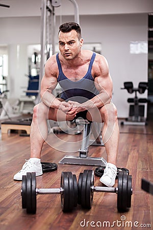 Athletic man resting on a bench at the gym