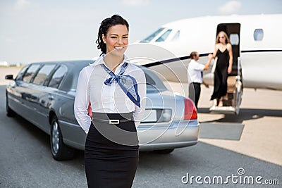 Attractive Airhostess Standing Against Limousine