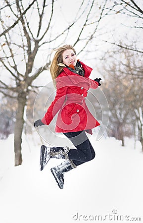 Attractive blonde girl with gloves, red coat and red hat posing in winter snow. Beautiful woman in the winter scenery. Young woman