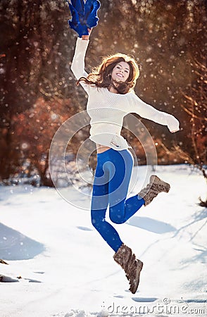 Attractive brunette girl with white sweater posing playing in winter scenery. Beautiful young woman with long hair enjoying snow