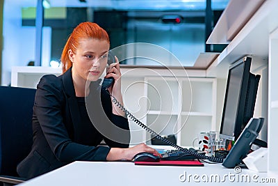 Attractive business woman in office cubicle on the phone